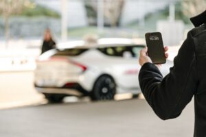 Reisende holder mobilen med en hvit taxi i bakgrunnen