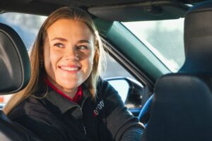 Smilende person i 07000-uniform vender seg mot baksetet